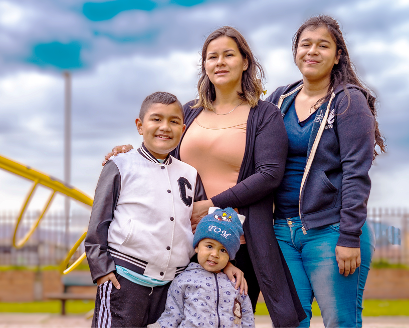Two young boys standing with older sister and mother