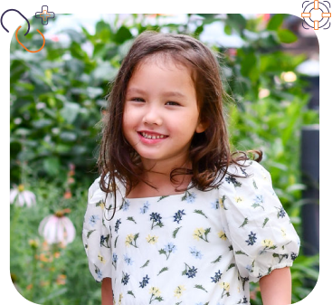 Little girl in a floral dress with blue shoes standing on a deck