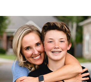 Mamá con cabello rubio con una camisa azul abrazando a su pequeño.