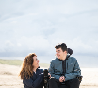 Woman with a powered wheelchair user on a beach.